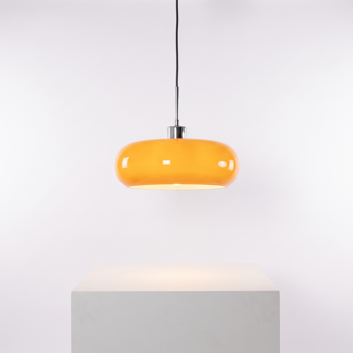 Bauhaus Retro Glass Pendant Light in Orange shade on a white display plinth
